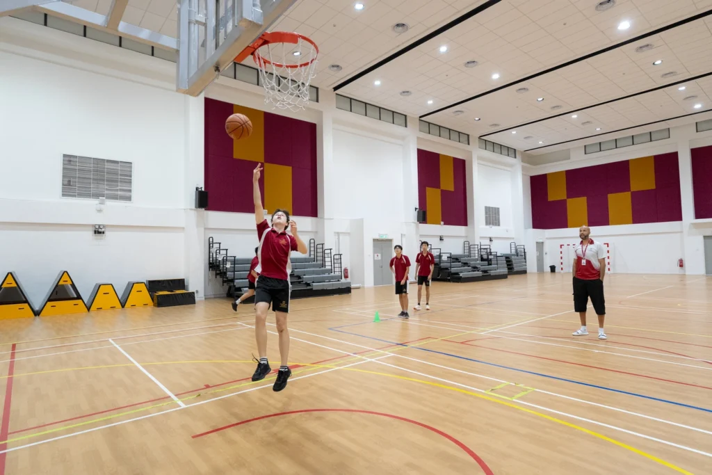 A student goes up for a layup in the sports hall.