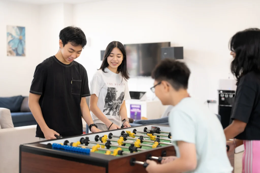 Boarders play table football together in the residence common room.