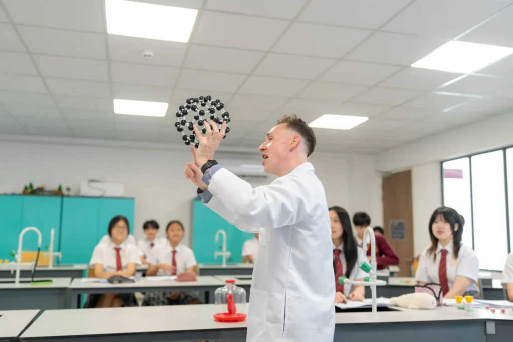 A chemistry teacher demonstrates with a molecular model to a class of Secondary students.