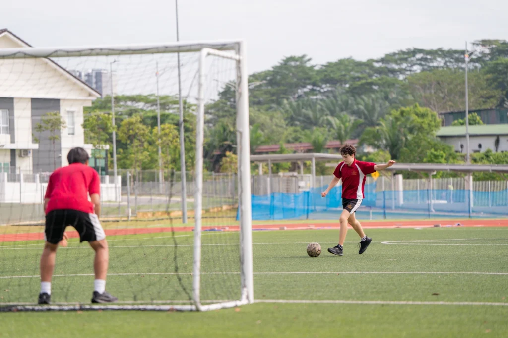 A student shoots at goal on the school pitch.