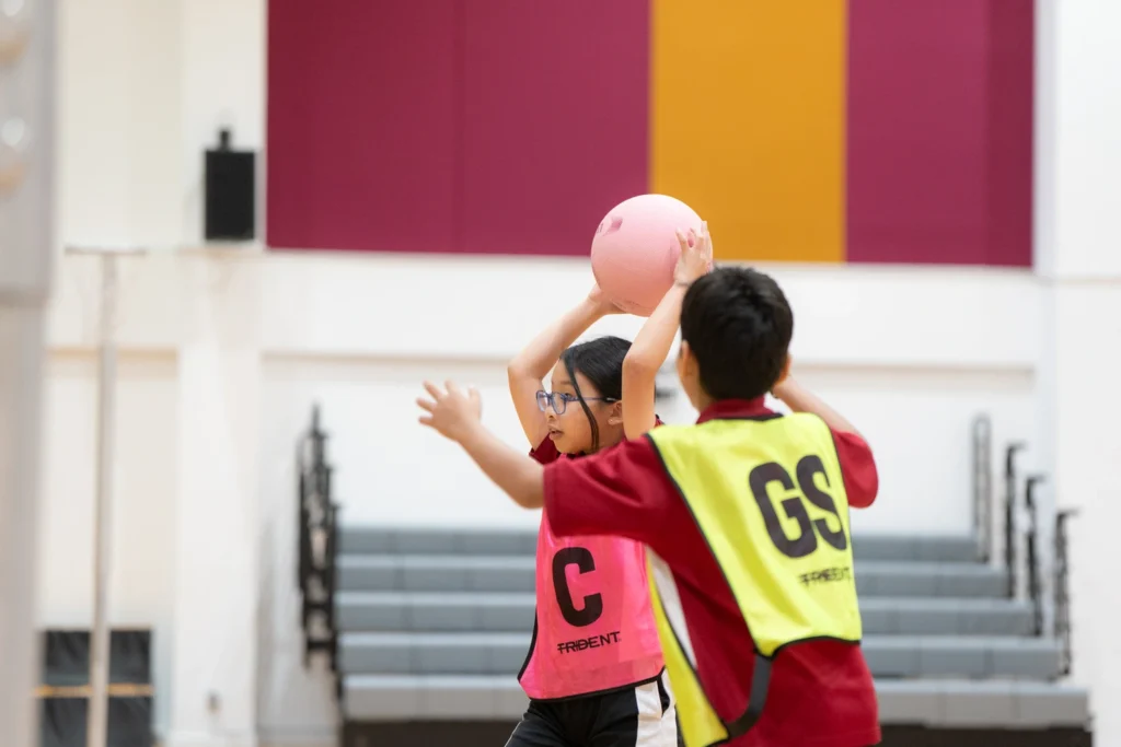 Students reach for the ball during a netball game.