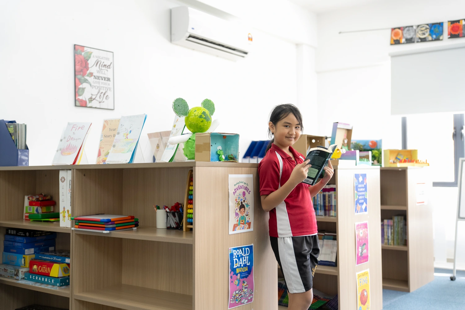 A Primary student reading a book in the school library.