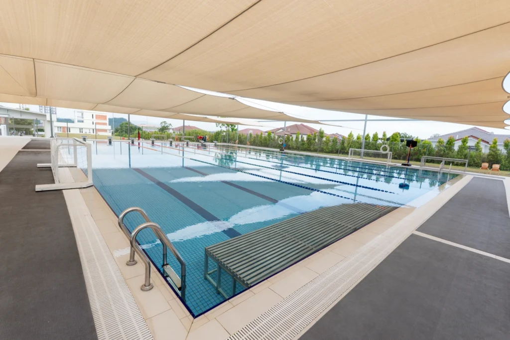 An outdoor swimming pool under a large canopy with clear blue water and lane dividers.