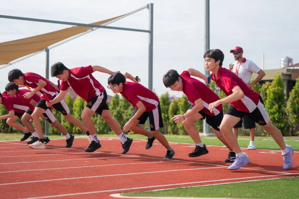Secondary students on the starting line of a sprint on the school running track.