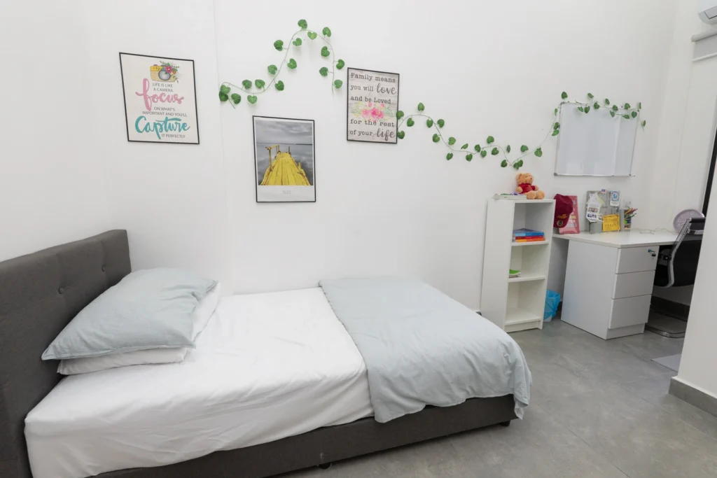 A boarding bedroom with a single bed, desk and storage.