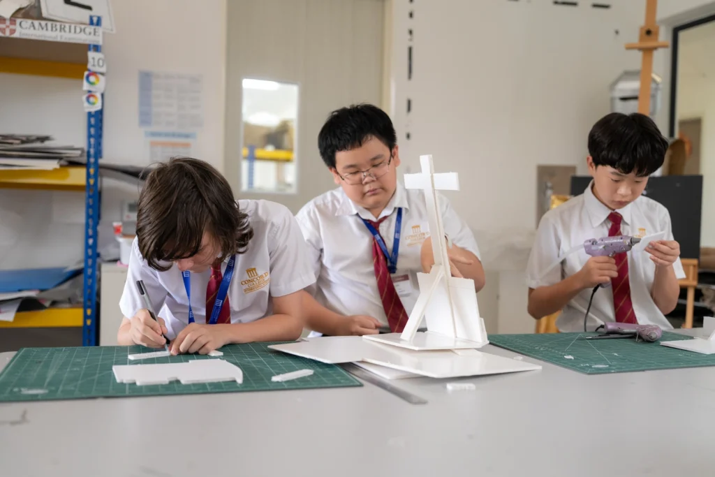 Students working on a project at the cutting mats in the design and technology room.