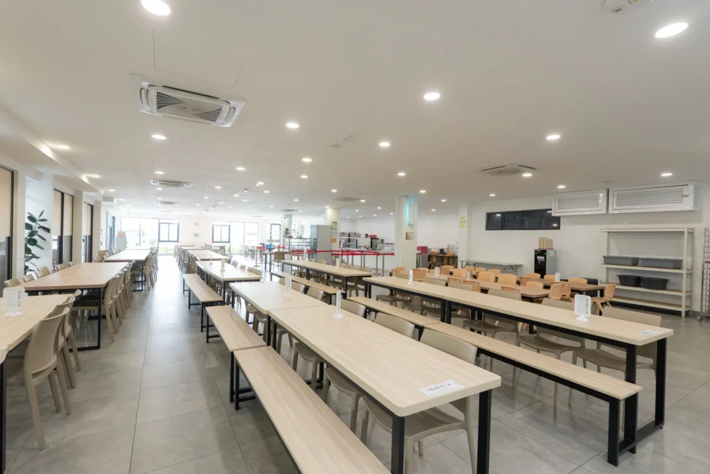 The dining hall with long refectory tables and bench seating.