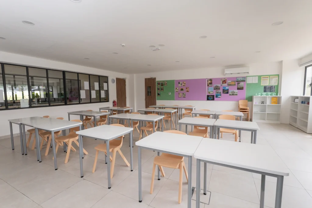 A secondary classroom with desks in rows and display boards along the back wall.