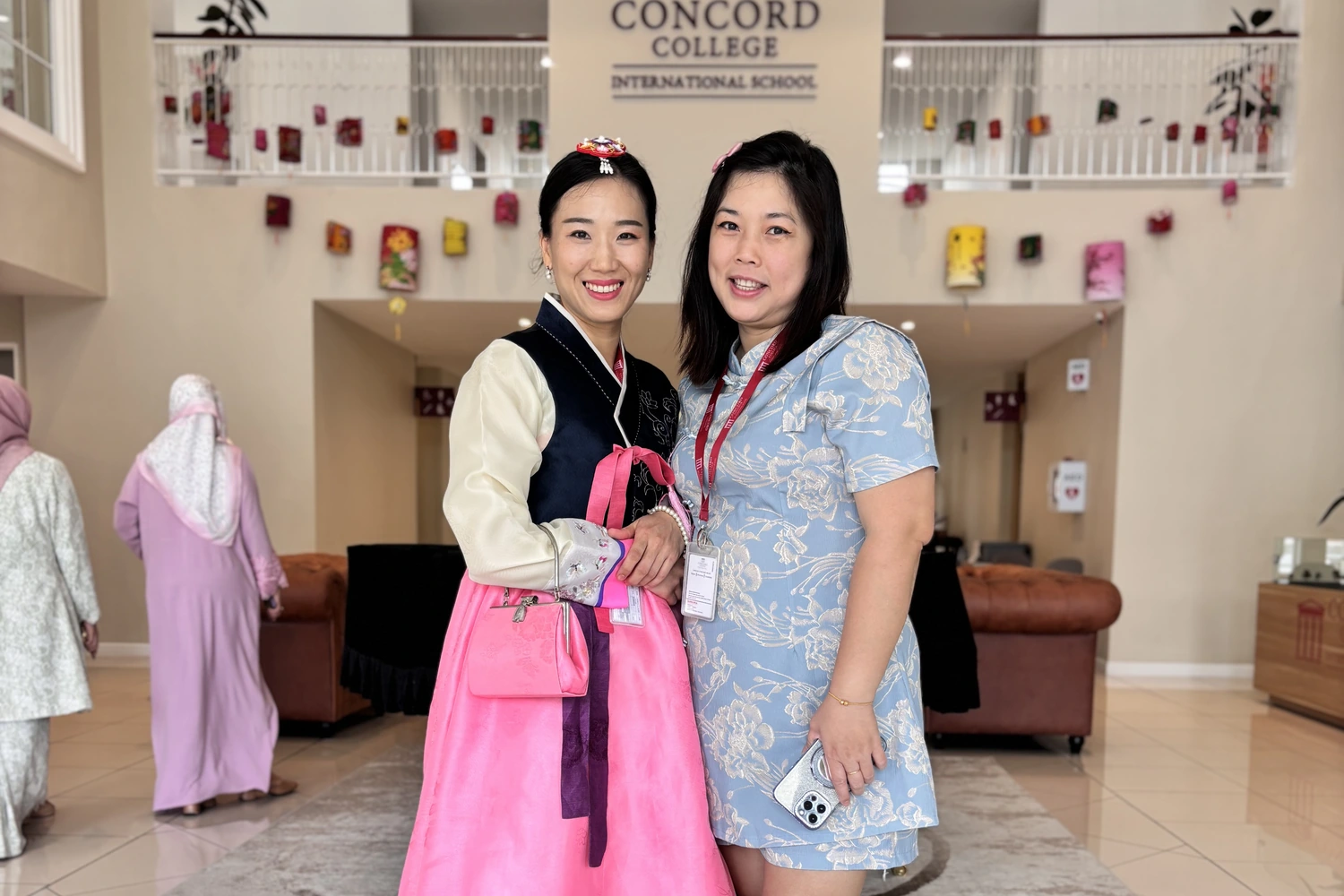 Two members of staff in cultural dress in the school foyer.