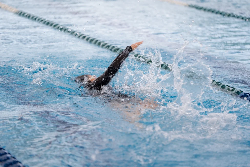 A swimmer mid-stroke in the school pool during a swimming lesson.