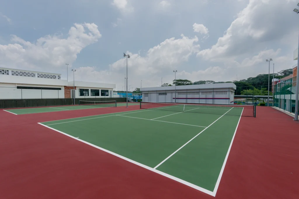 An outdoor tennis court with the campus buildings beyond.