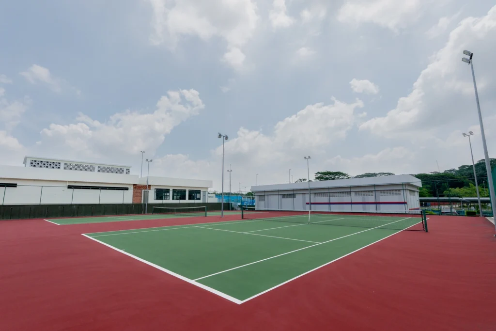 The outdoor tennis court seen from the baseline, with the campus buildings beyond.