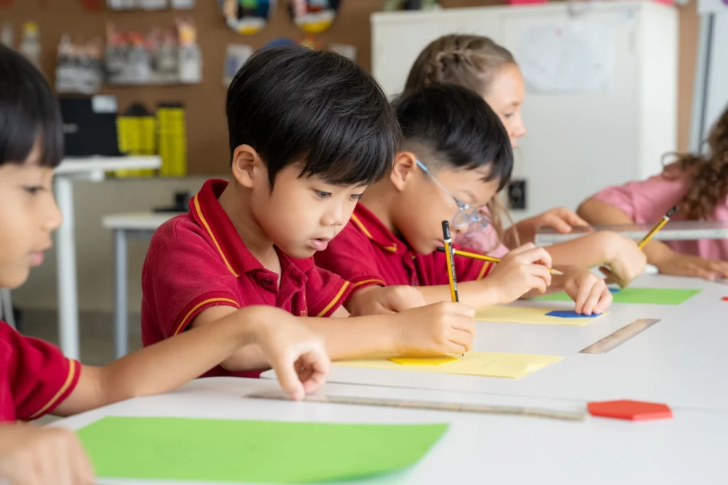Year 1 pupils work side by side on a writing task in the classroom.